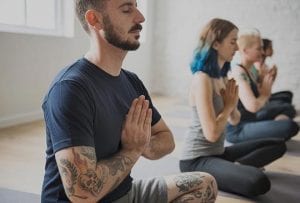 men and woman performing self care meditation yoga